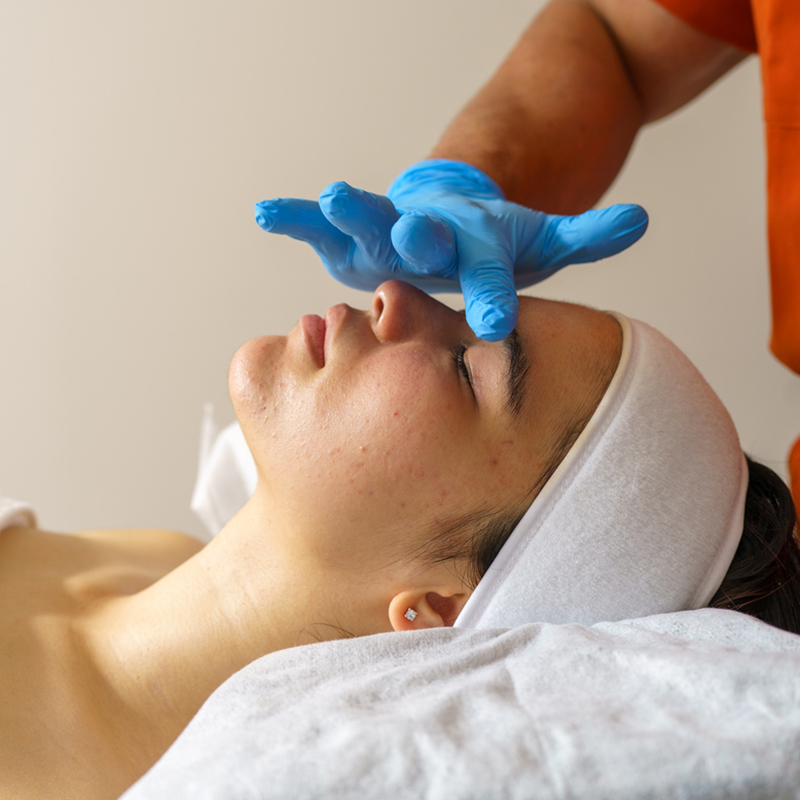 Person receiving a facial treatment with protective gloves in a spa setting.