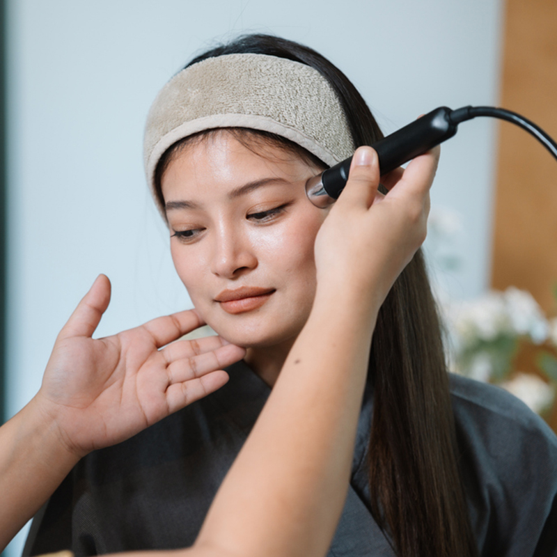 A woman receiving a facial treatment with a microdermabrasion tool in a spa setting.