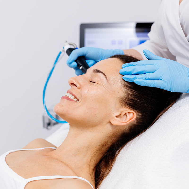 A woman receiving skincare treatment with a hydrofacial device.