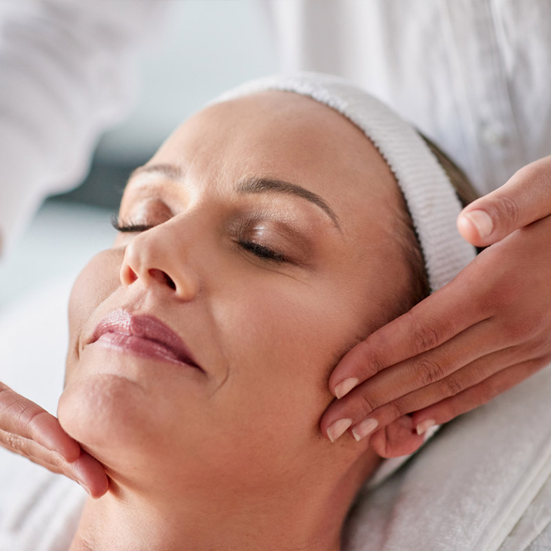 A woman receiving a facial massage at a spa.