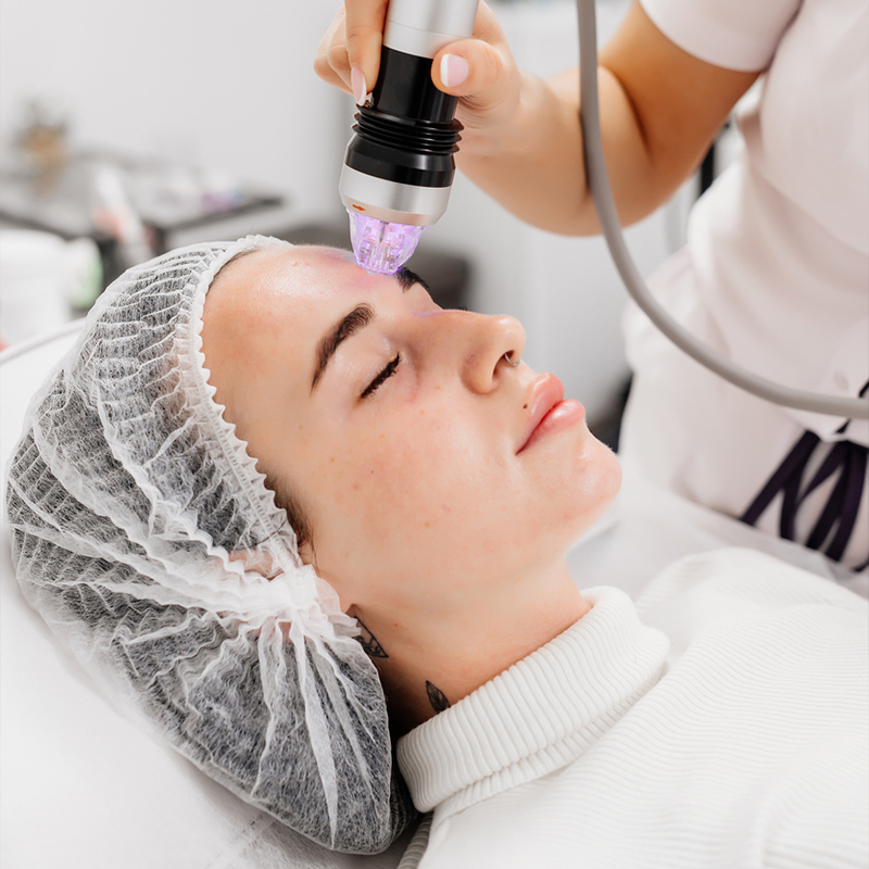 A person receiving facial skin treatment with a medical device.